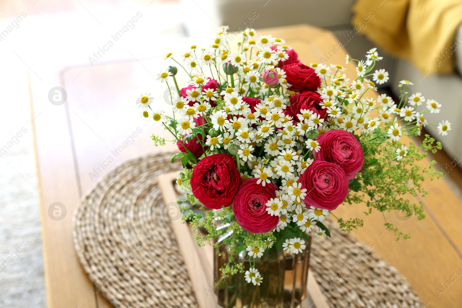 Photo of Beautiful ranunculus flowers and chamomiles in vase on table indoors