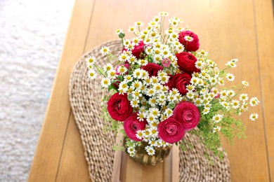 Photo of Beautiful ranunculus flowers and chamomiles in vase on table indoors, above view