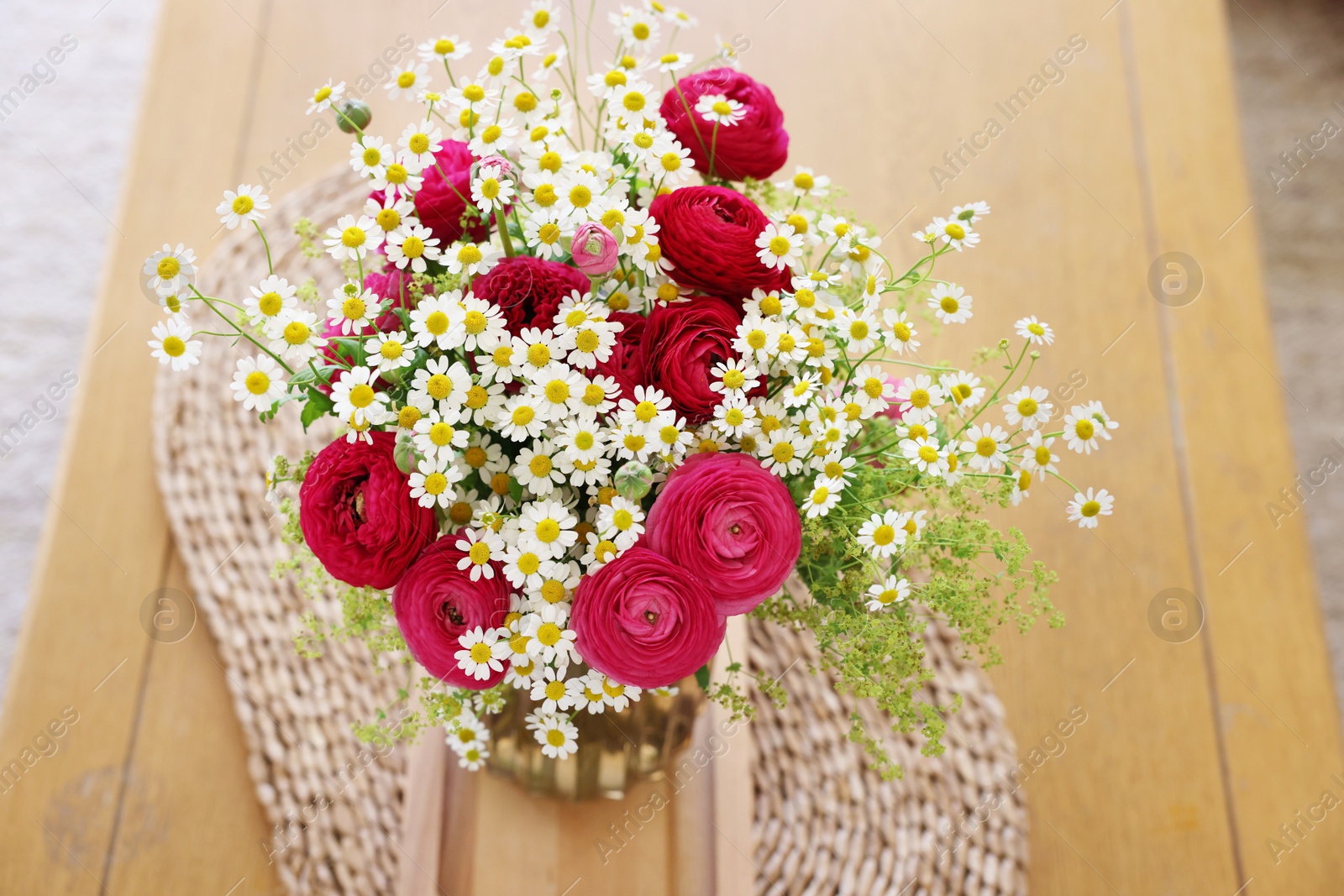 Photo of Beautiful ranunculus flowers and chamomiles in vase on table indoors