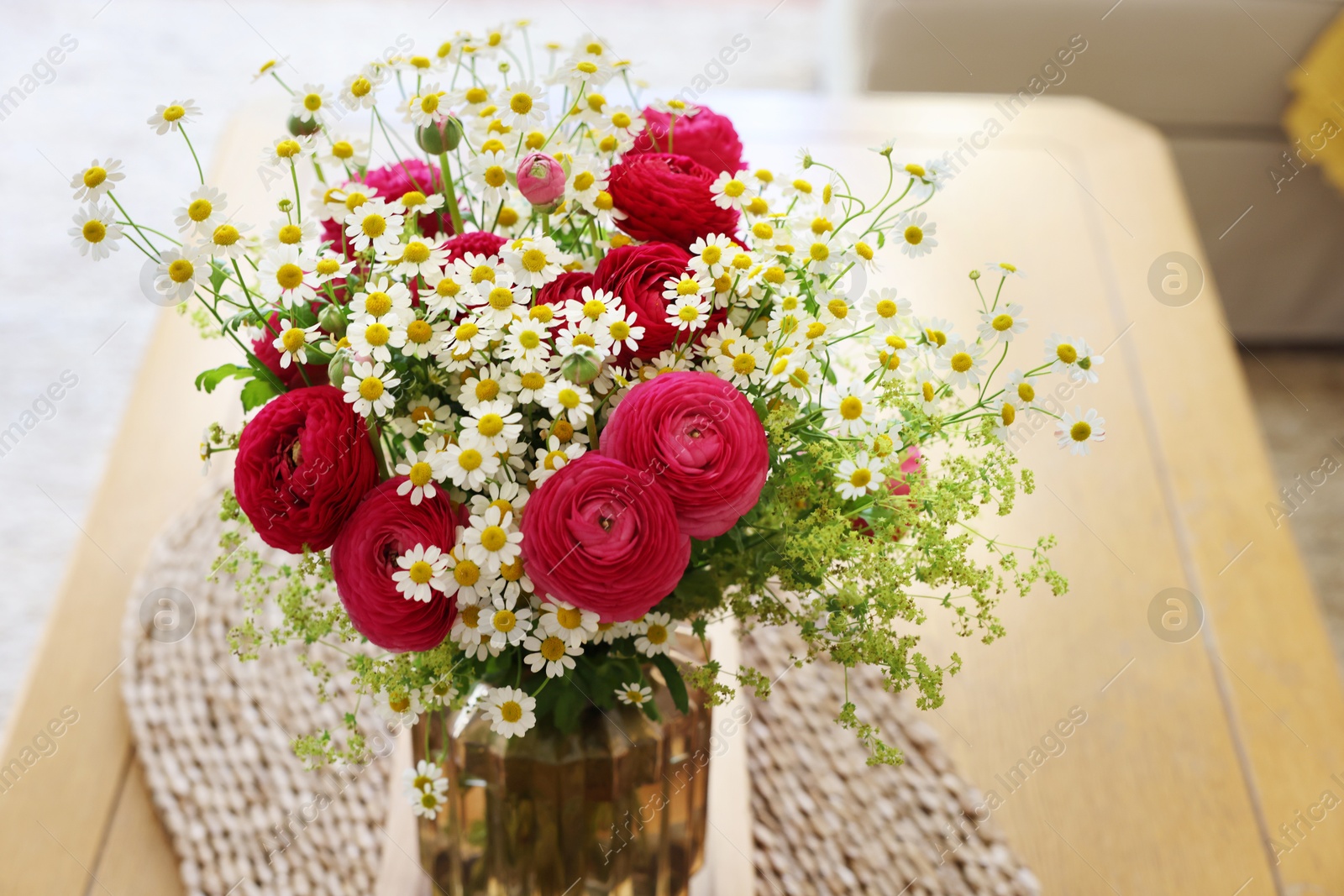 Photo of Beautiful ranunculus flowers and chamomiles in vase on table indoors