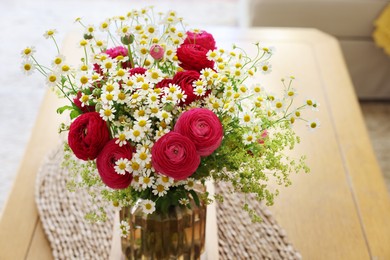 Photo of Beautiful ranunculus flowers and chamomiles in vase on table indoors