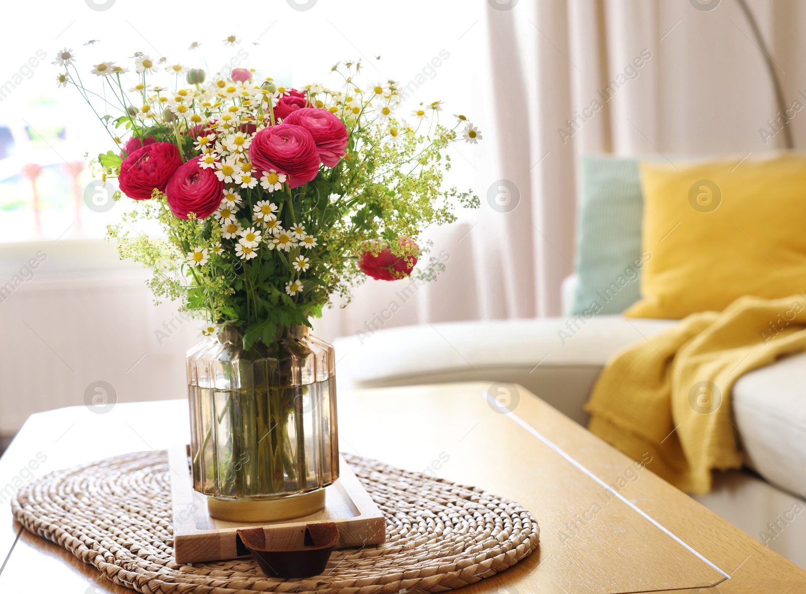 Photo of Beautiful ranunculus flowers and chamomiles in vase on table indoors