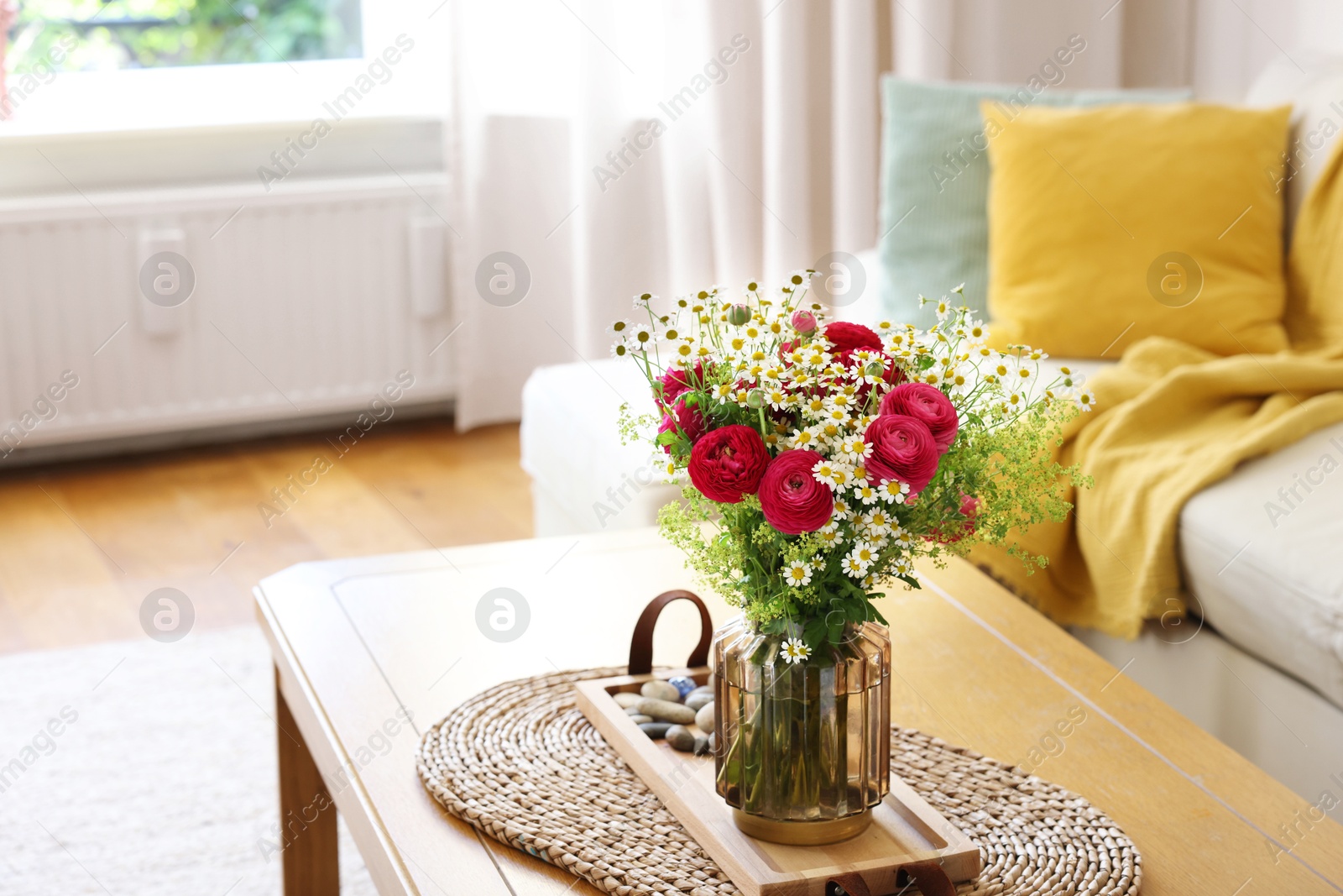 Photo of Beautiful ranunculus flowers and chamomiles in vase on table indoors. Space for text