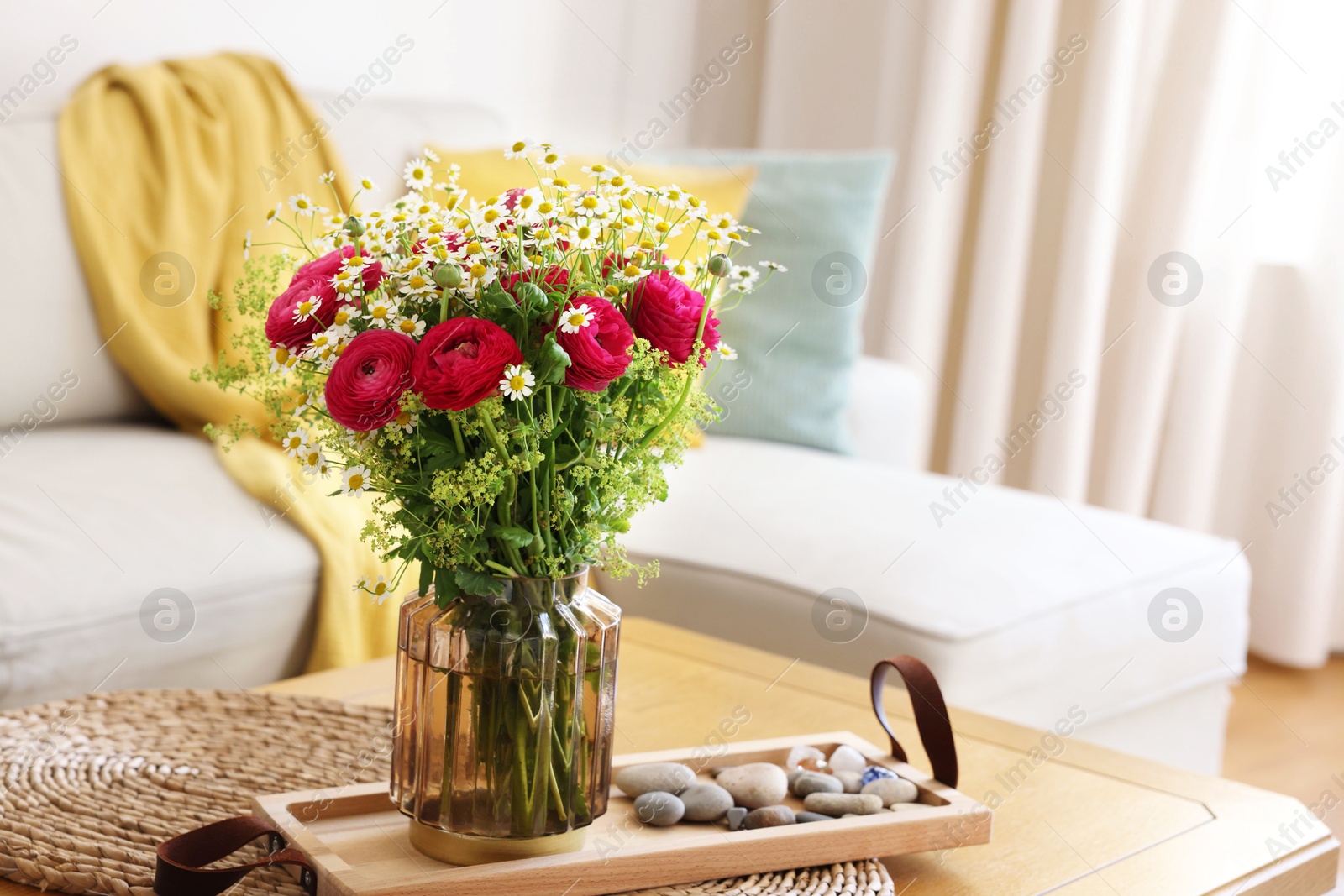 Photo of Beautiful ranunculus flowers and chamomiles in vase on table indoors