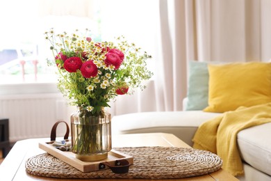 Photo of Beautiful ranunculus flowers and chamomiles in vase on table indoors