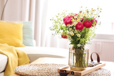 Photo of Beautiful ranunculus flowers and chamomiles in vase on table indoors