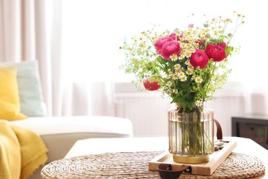 Photo of Beautiful ranunculus flowers and chamomiles in vase on table indoors