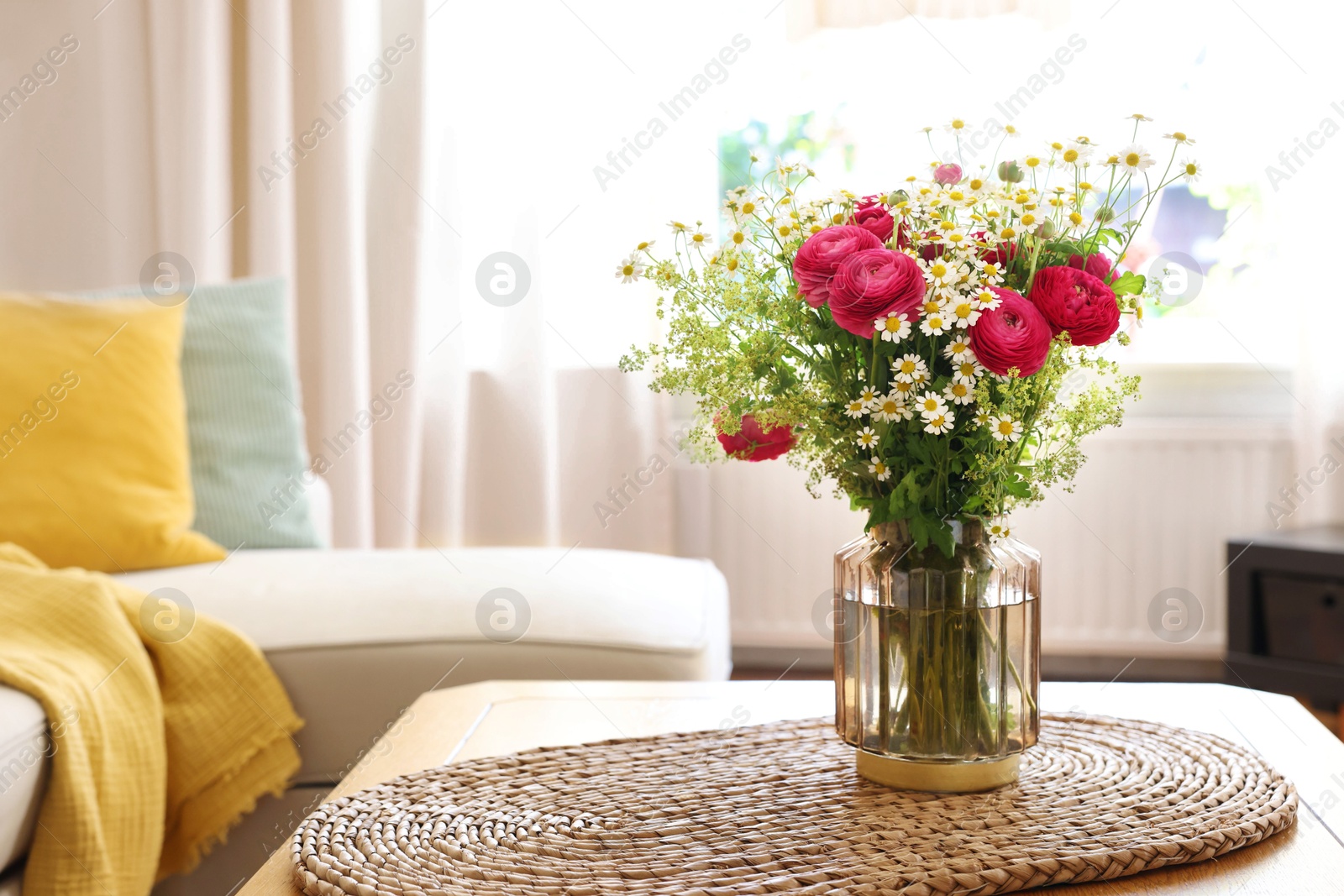 Photo of Beautiful ranunculus flowers and chamomiles in vase on table indoors