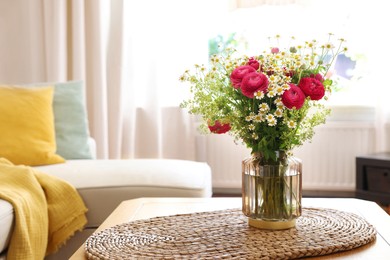 Photo of Beautiful ranunculus flowers and chamomiles in vase on table indoors