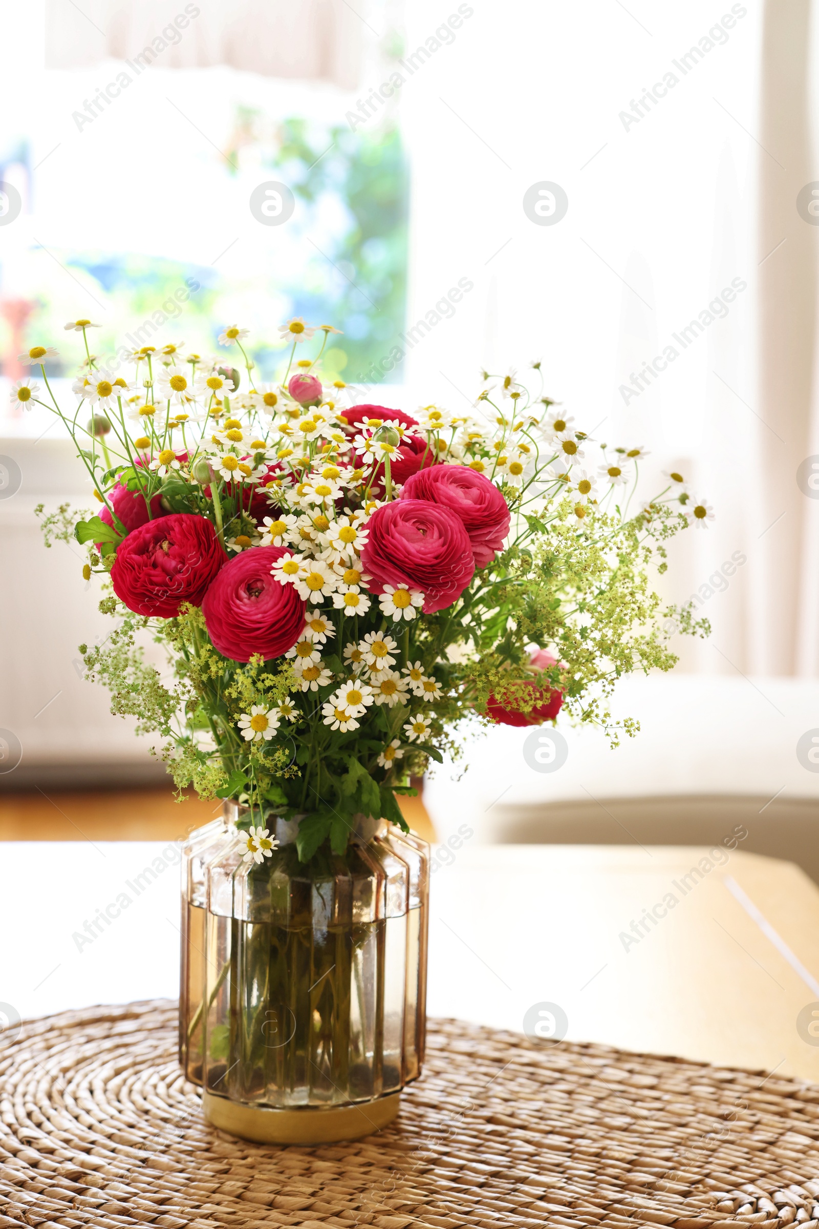 Photo of Beautiful ranunculus flowers and chamomiles in vase on table indoors