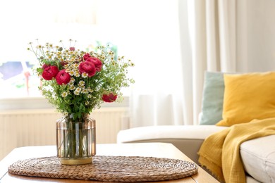 Beautiful ranunculus flowers and chamomiles in vase on table indoors