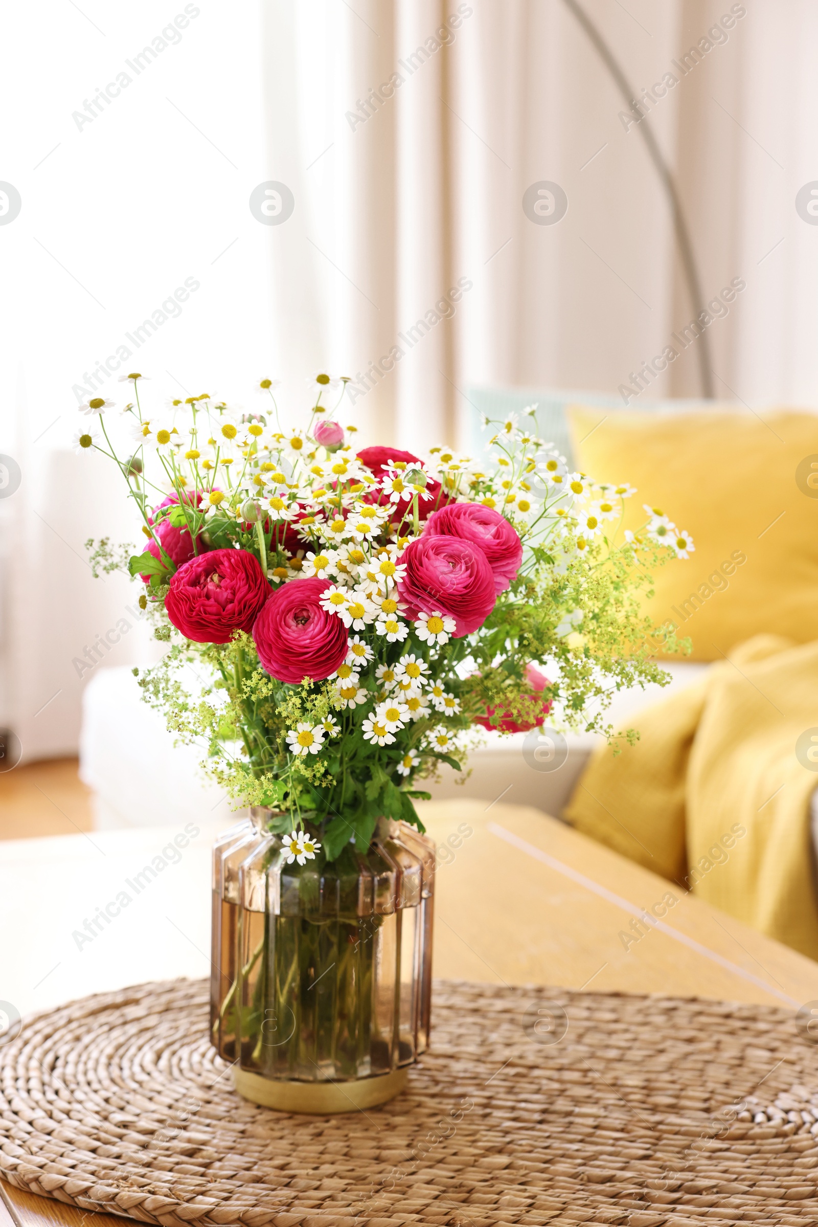 Photo of Beautiful ranunculus flowers and chamomiles in vase on table indoors