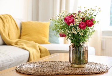 Beautiful ranunculus flowers and chamomiles in vase on table indoors