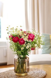 Photo of Beautiful ranunculus flowers and chamomiles in vase on table indoors