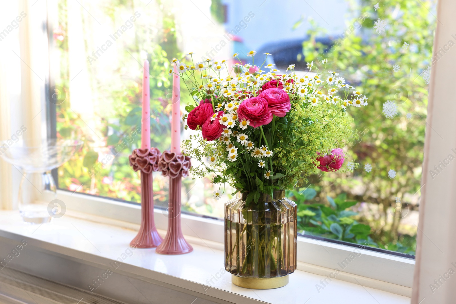 Photo of Beautiful ranunculus flowers and chamomiles in vase on windowsill indoors