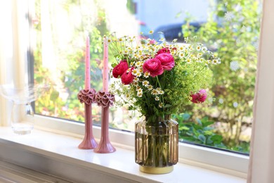 Photo of Beautiful ranunculus flowers and chamomiles in vase on windowsill indoors