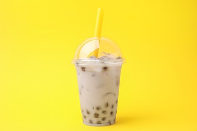 Tasty milk bubble tea in plastic cup on yellow background