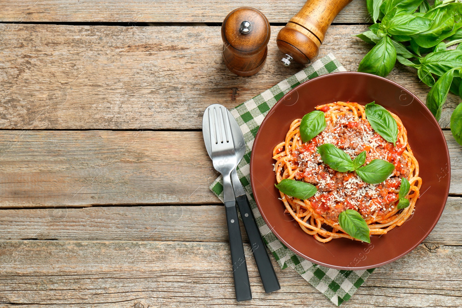 Photo of Delicious pasta bolognese with basil served on wooden table, top view. Space for text