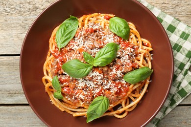 Photo of Delicious pasta bolognese with basil on wooden table, top view