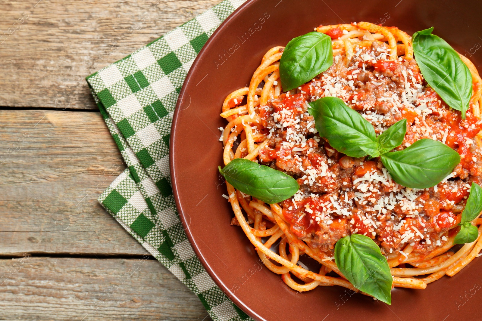 Photo of Delicious pasta bolognese with basil on wooden table, top view