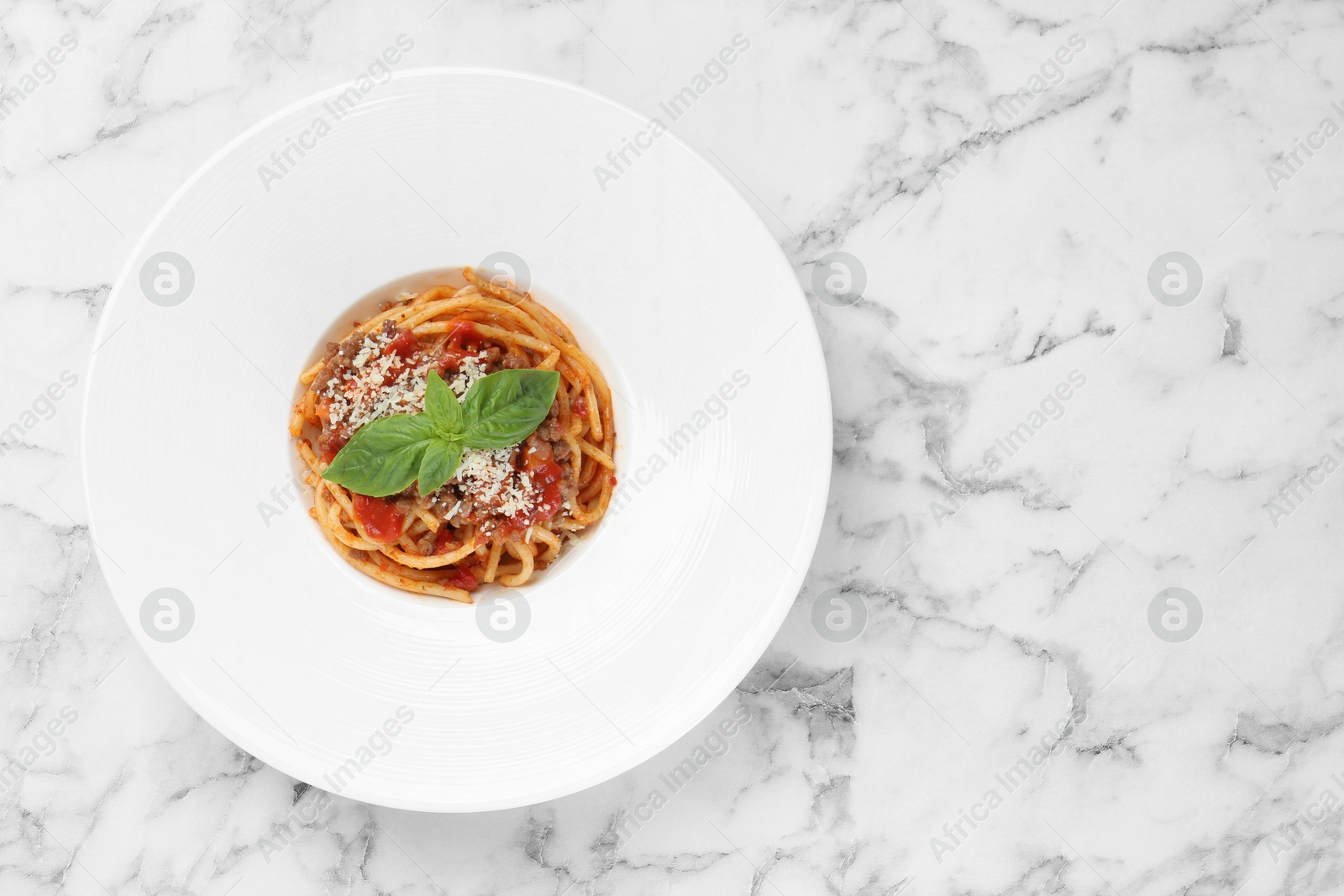 Photo of Delicious pasta bolognese with basil on white marble table, top view. Space for text