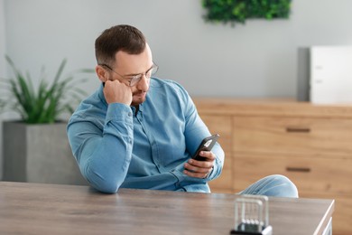 Handsome man looking at smartphone in office