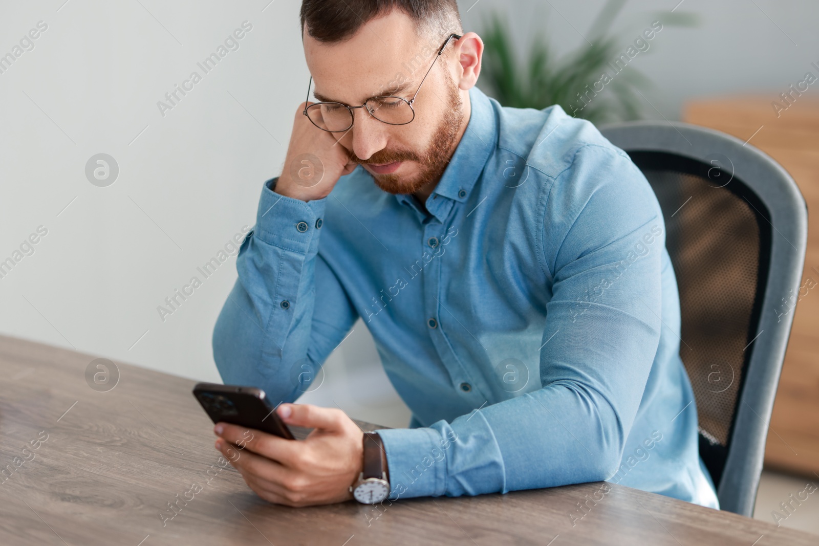 Photo of Handsome man looking at smartphone in office