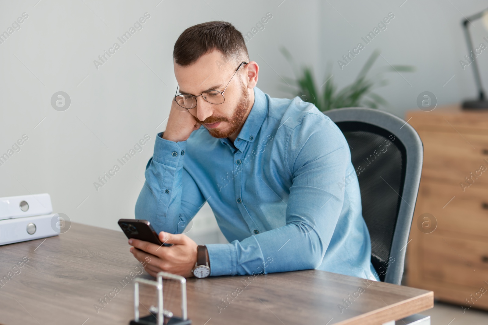 Photo of Handsome man looking at smartphone in office