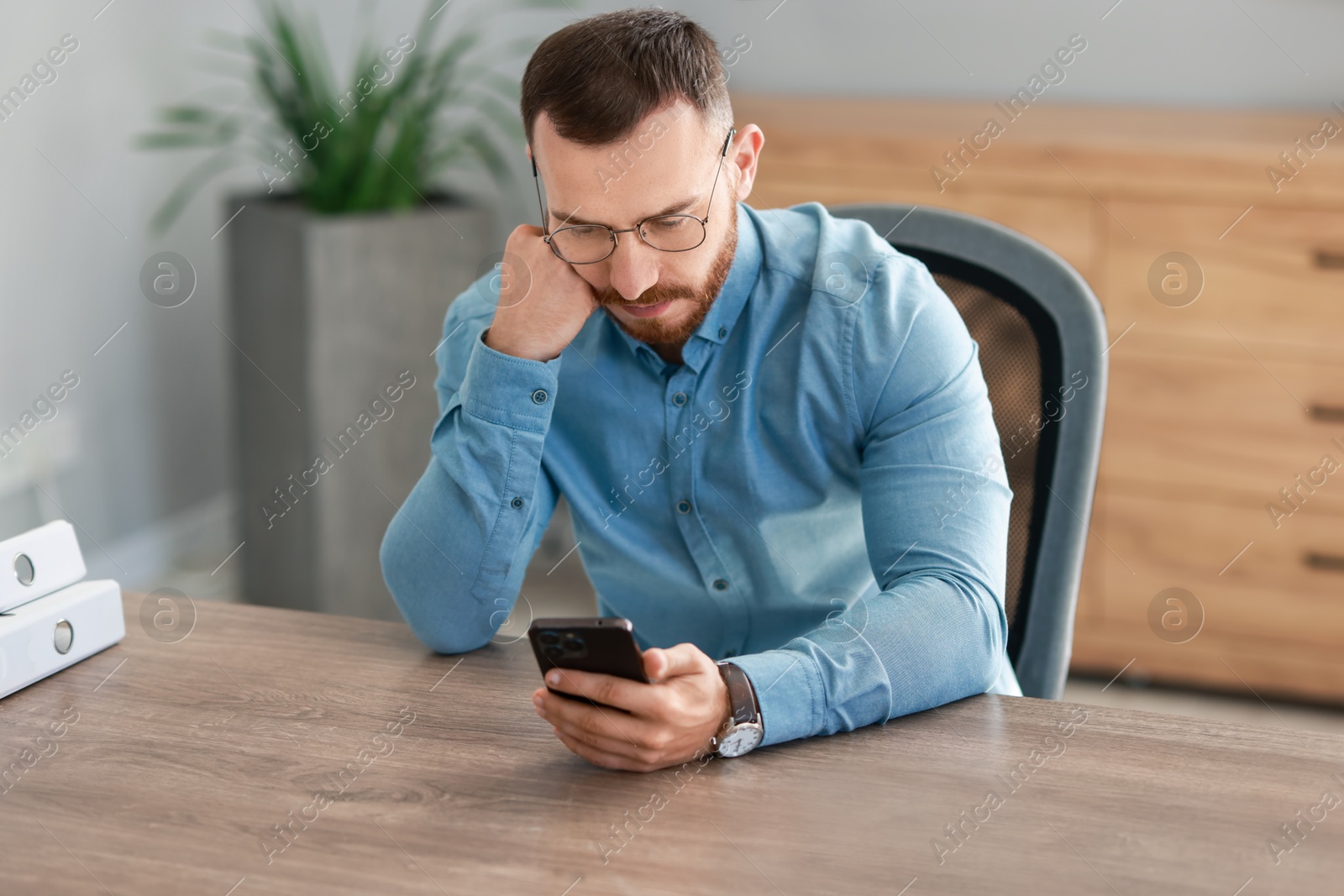 Photo of Handsome man looking at smartphone in office