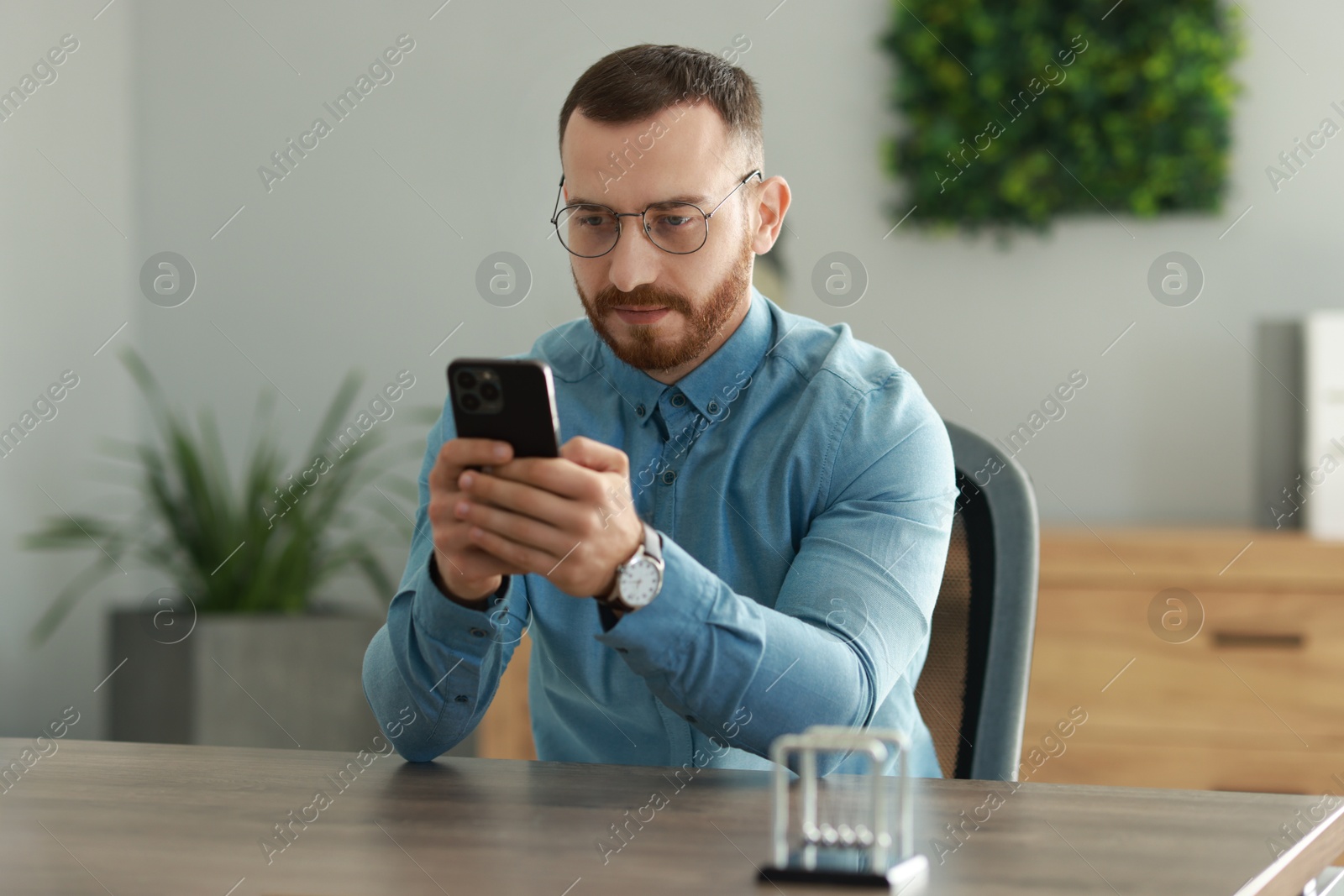 Photo of Handsome man looking at smartphone in office