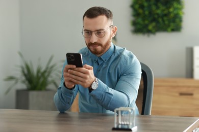 Handsome man looking at smartphone in office