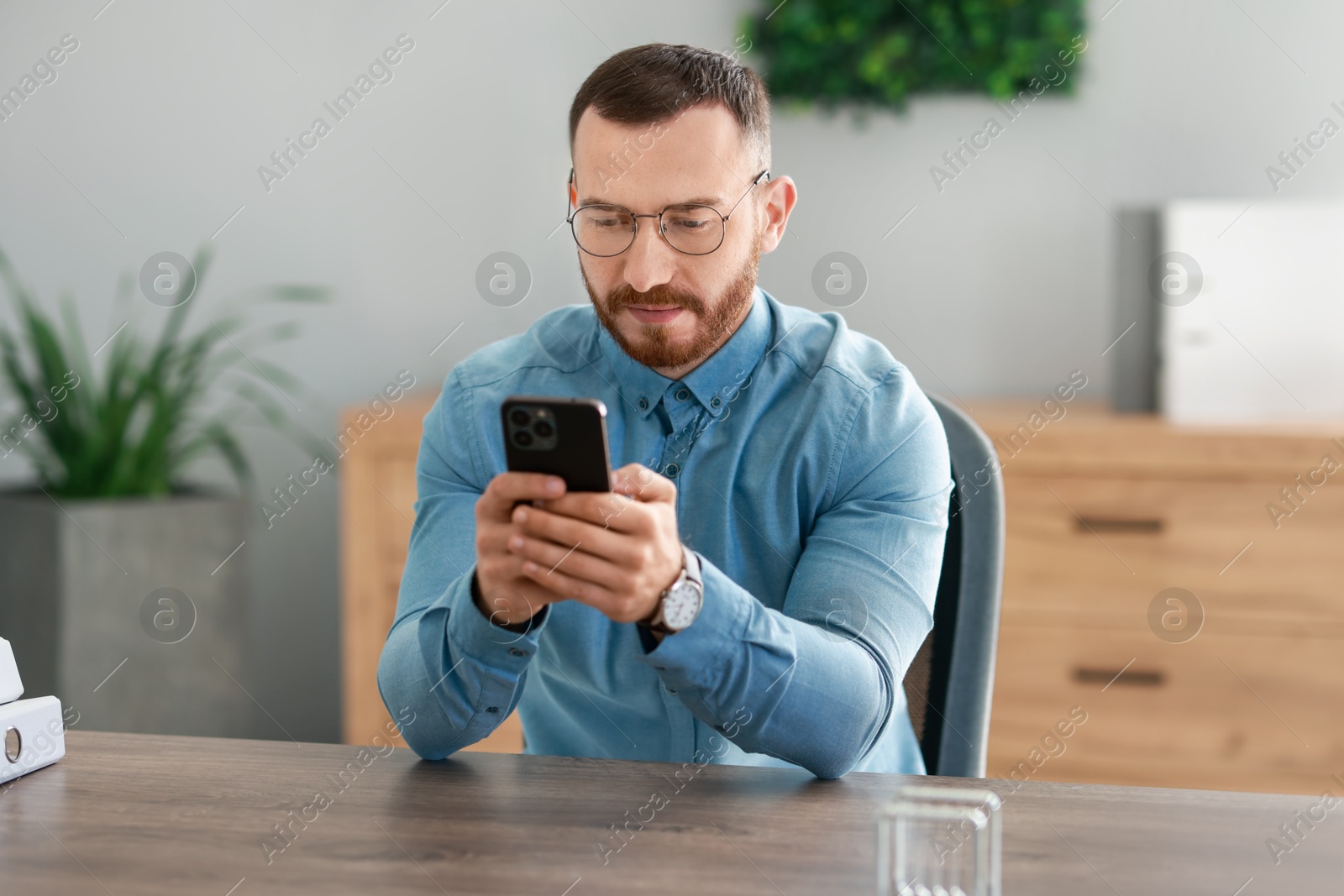 Photo of Handsome man looking at smartphone in office