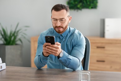 Handsome man looking at smartphone in office