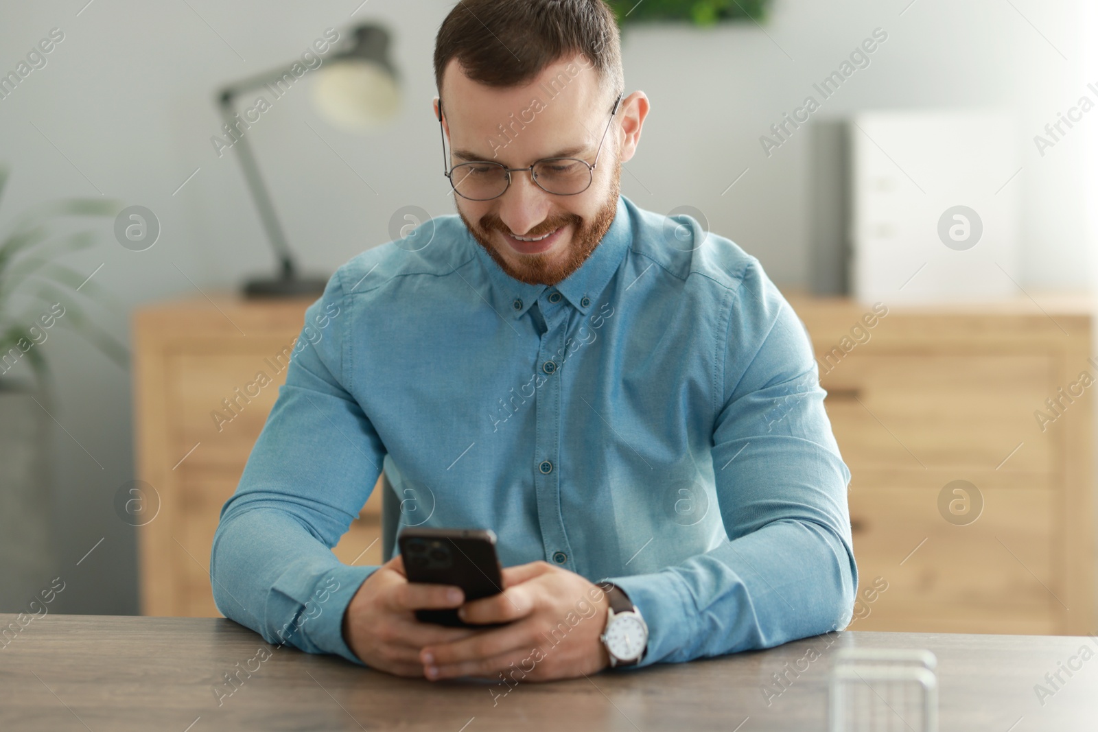 Photo of Handsome man looking at smartphone in office