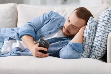 Handsome man looking at smartphone on sofa