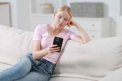 Photo of Beautiful woman using smartphone on sofa indoors