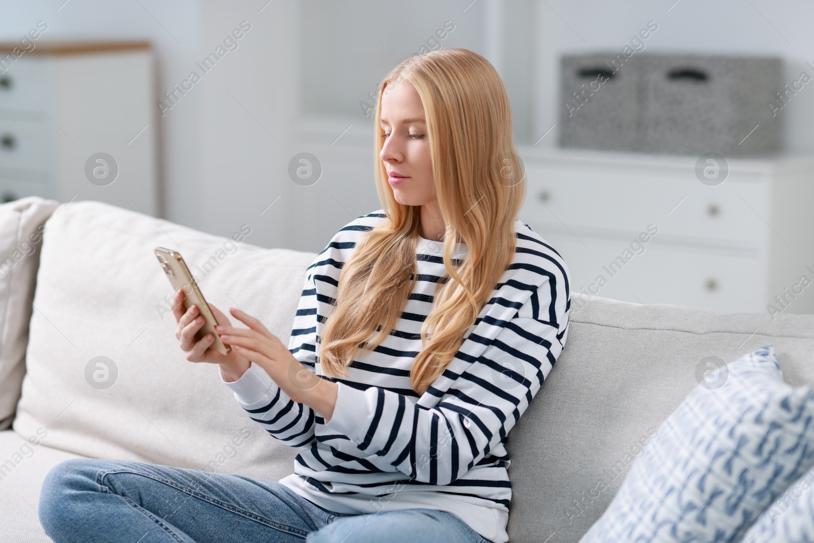 Photo of Beautiful woman using smartphone on sofa indoors