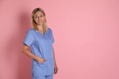 Portrait of nurse in medical uniform on pink background, space for text