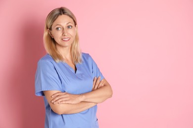 Portrait of nurse in medical uniform on pink background, space for text