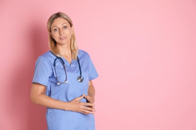 Photo of Portrait of doctor in medical uniform with stethoscope on pink background, space for text