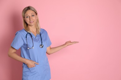 Photo of Portrait of doctor in medical uniform with stethoscope on pink background, space for text