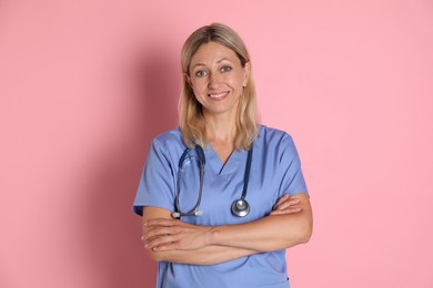 Portrait of doctor in medical uniform with stethoscope on pink background