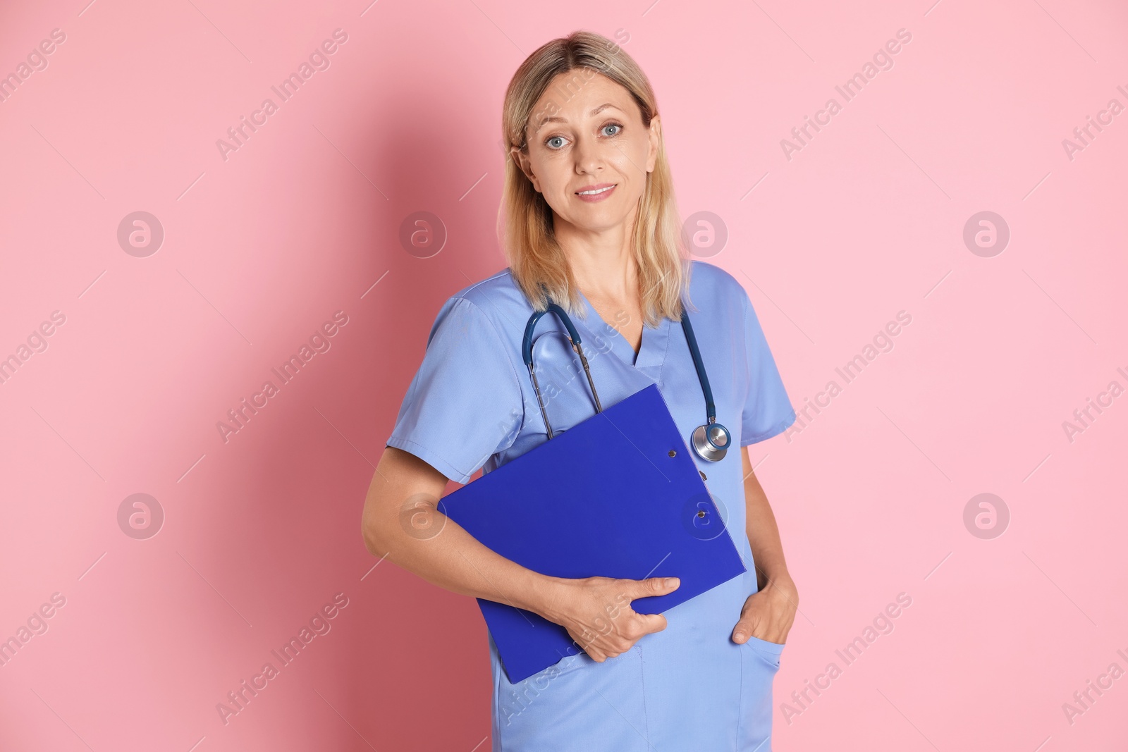 Photo of Portrait of doctor in medical uniform with stethoscope and clipboard on pink background