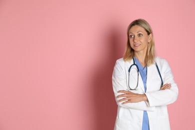 Photo of Doctor in medical uniform with stethoscope on pink background, space for text