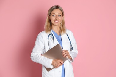 Photo of Doctor in medical uniform with stethoscope and laptop on pink background