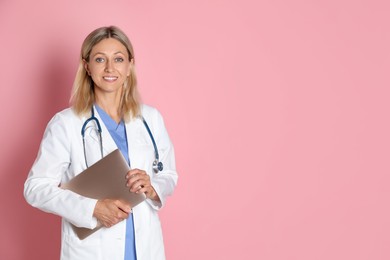 Photo of Doctor in medical uniform with stethoscope and laptop on pink background, space for text