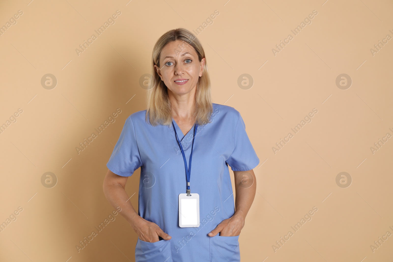 Photo of Portrait of nurse in medical uniform with badge on beige background