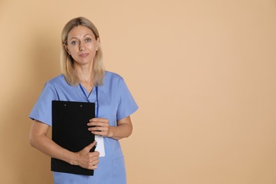 Nurse in medical uniform with badge and clipboard on beige background, space for text