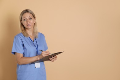 Nurse in medical uniform with badge and clipboard on beige background, space for text