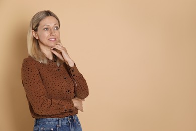 Portrait of beautiful smiling woman on beige background, space for text